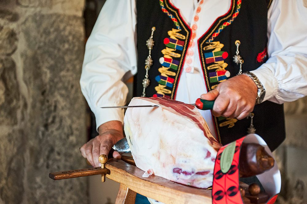 man slicing smoked ham